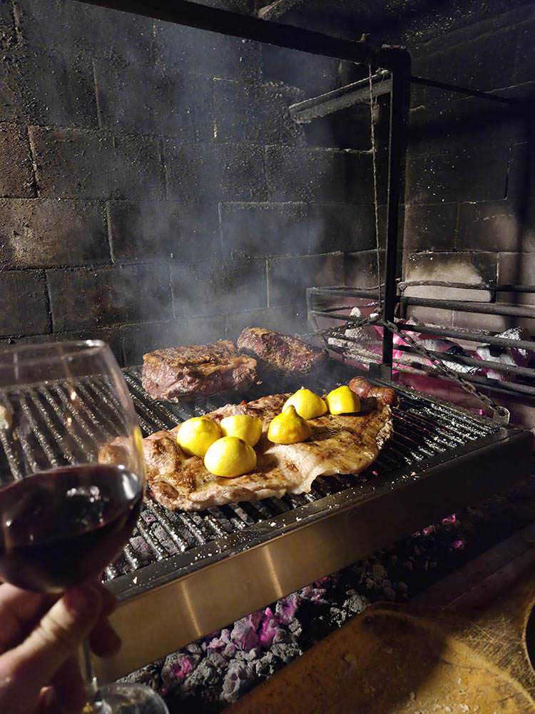 Copa de vino y chimichurri junto a un asado